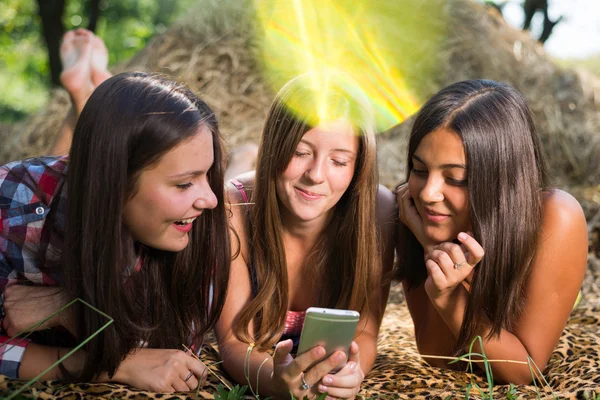 Три девочки-подростки пользуются телефоном на улице — стоковое фото