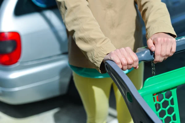 Mulher com carrinho de compras no estacionamento — Fotografia de Stock