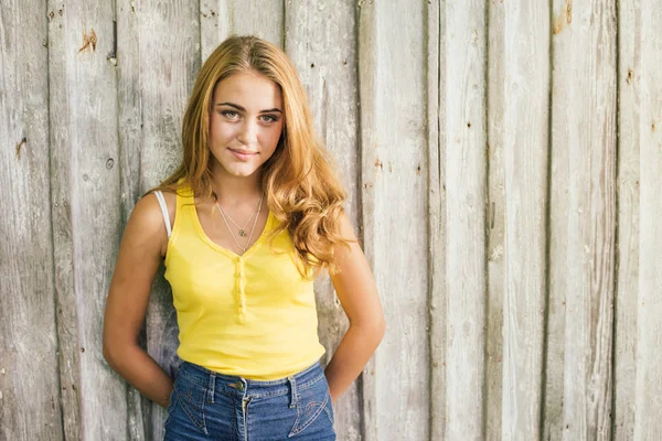 Moda mujer rubia joven en camiseta amarilla sobre fondo de madera pálida — Foto de Stock