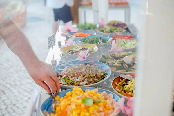 Primer plano de la barra de ensaladas con una variedad de ingredientes. El hombre se sirve con ensalada —  Fotos de Stock