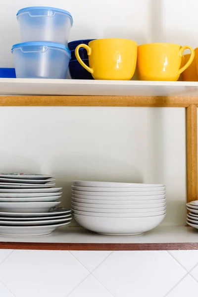 Holzschrank mit Stapeln von keramischen Tellern, Tassen und Kunststoffbehältern — Stockfoto