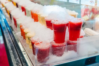 Meyve suyu karışımı. Plastik bardaklara yerleştirilmiş buzlu. İçinde çatal olan bir market tezgahında.