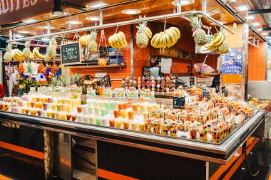 Meyve salatası plastik bardaklara yerleştirilmiş içinde çatal olan bir market tezgahında, sağlıklı atıştırmalıklar.