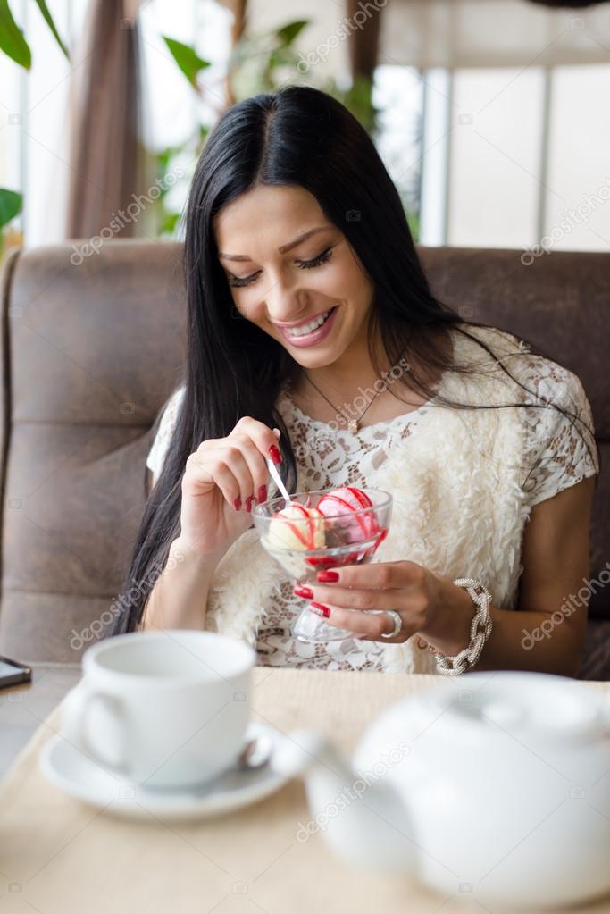 picture of closeup portrait on gorgeous brunette young pretty woman eating icecream having fun happy smiling in cozy coffee shop or restaurant interior background