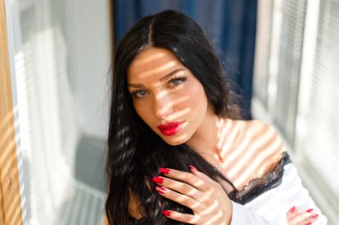 görüntü portre portre mavi gözlü seksi esmer kız güzel kırmızı ruj genç kadınla vakit sensually kameraya ışıklı güneş perdeleri arka plan üzerinde seyir