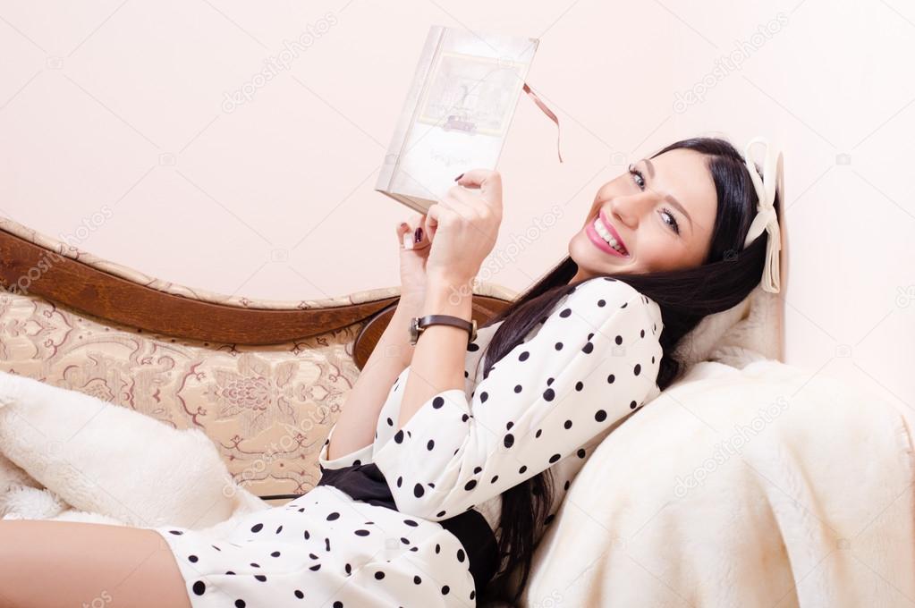 Beautiful sexy pinup woman funny brunette girl having fun reading book happy smiling and looking at camera relaxing on coach or sofa in white polka dots dress picture Stock Photo by ©rosipro Beautiful sexy pinup woman funny brunette girl having fun reading book happy smiling and looking at camera relaxing on coach or sofa in white polka dots dress picture Stock Photo by ©rosipro