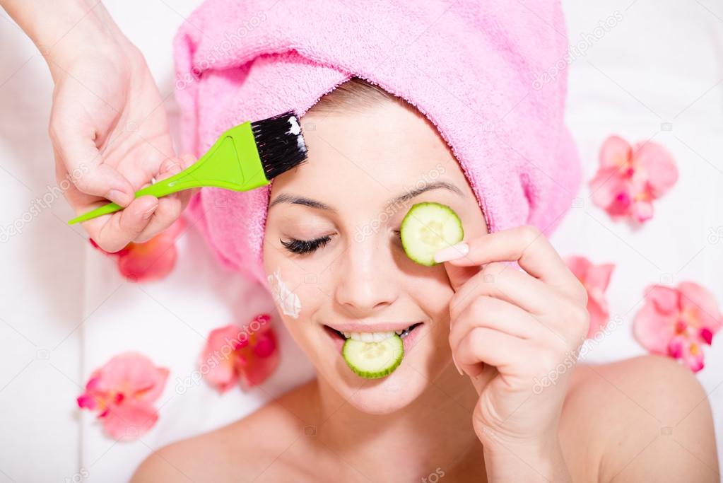 spa fun: closeup image of funny girl beautiful blond young woman having multi treatment procedures happy smiling eyes closed on white background