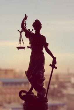 picture of goddess Themis or Lady Justice standing on window holding sword blindfold on the city outdoors background