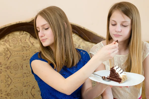 Diet & creamy chocolate cake: close up portrait of 2 beautiful young women cute blond sisters or girls friends having fun eating delicious cake together in blue and white dress & one looking away — Stock Photo, Image