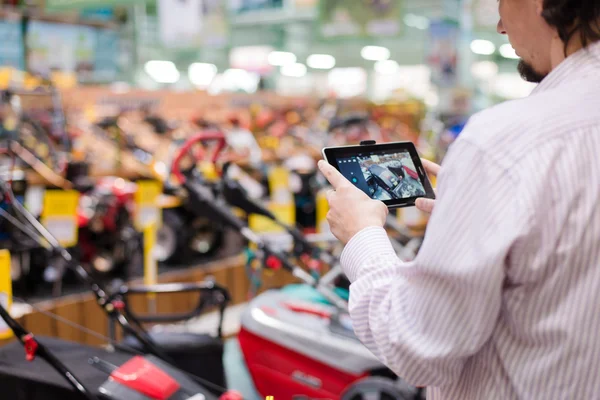 Kundin fotografiert auf dem Tablet-PC Rasenmäher im Supermarkt — Stockfoto