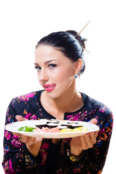 Belle femme drôle avec des yeux bleus & lèvres rouges s'amusant tenant plaque de sushi dans les mains & montre la langue heureux sourire en regardant dans l'appareil photo sur fond blanc copie image portrait gros plan — Photo