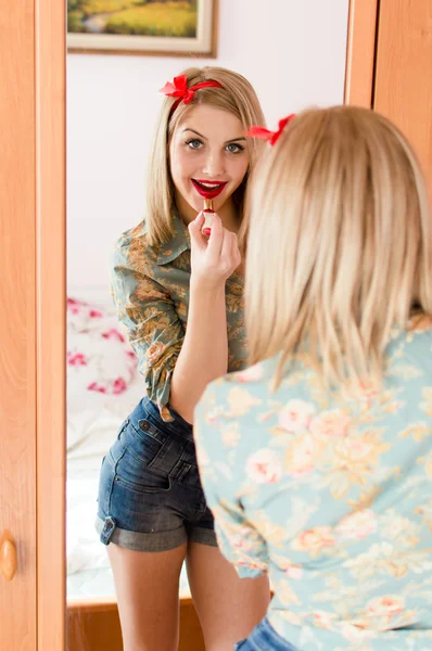 Imagem da sedutora jovem loira pinup menina bela mulher sexy se divertindo posando desenha no espelho lábios de batom vermelho feliz sorrindo e olhando para o retrato da câmera — Fotografia de Stock