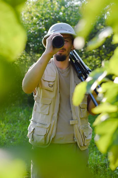 Voyage en safari : portrait de touriste ou explorateur scientifique mâle en casque de moelle s'amuser à observer à travers la portée sur la journée ensoleillée d'été bois verts copier fond d'espace — Photo