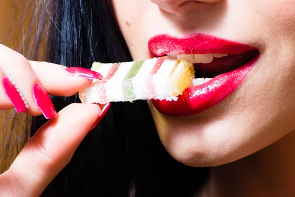 Hünnap, ısırma üzerinde tatlı şeker ile açık ağzı büyük diş bakımı diş, kırmızı baştan çıkarıcı dudaklar ve çivi resim güzel seksi kadın — Stok fotoğraf