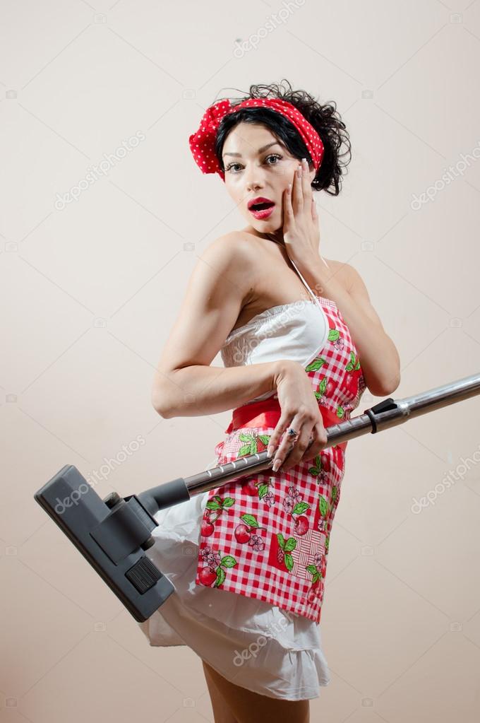 Picture of beautiful funny sexy pinup lady wearing apron & looking at camera surprised while vacuum cleaner sucked in her dress portrait on white or light wall copy space background portrait Stock Picture of beautiful funny sexy pinup lady wearing apron & looking at camera surprised while vacuum cleaner sucked in her dress portrait on white or light wall copy space background portrait Stock