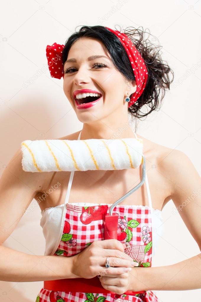 Closeup on pretty funny brunette sexy pinup girl holding paint bolster, having good time & fun looking at camera and laughing joyfully on white or light copy space background portrait picture Stock Closeup on pretty funny brunette sexy pinup girl holding paint bolster, having good time & fun looking at camera and laughing joyfully on white or light copy space background portrait picture Stock
