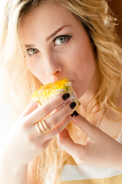 Closeup picture of eating alone large fruit creamy cake beautiful blond young lady sexy green eyes girl having fun happy smiling & looking at camera on bedroom background portrait — Stock Photo, Image