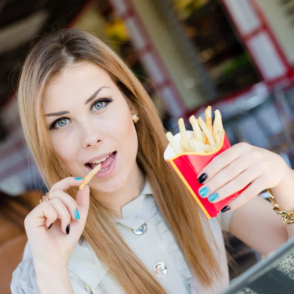 Jovem mulher desfrutando de fast food batatas fritas — Fotografia de Stock