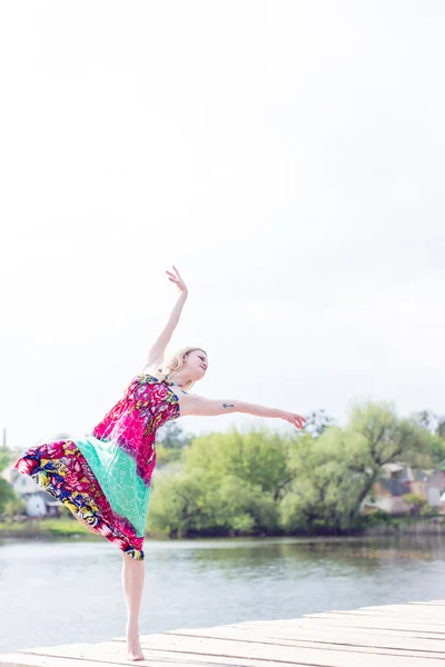 Joie dansante : posant belle blonde jeune femme mince profiter de s'étirer en robe longue lumière au lac d'eau sur l'été vert à l'extérieur & ciel blanc copie image de fond portrait de l'espace — Photo
