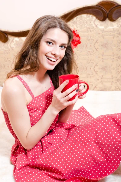 Девушка в красном платье держит чашку горячего напитка — стоковое фото