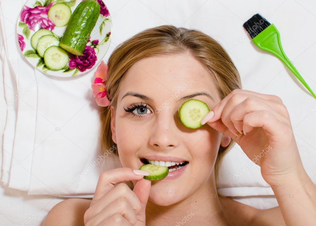 Girl lying with slices of cucumber in hands