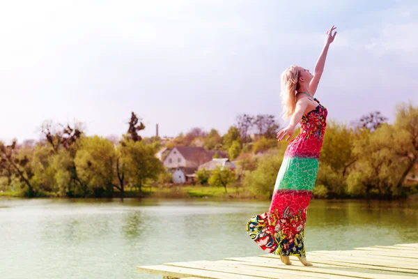 Slim woman stretching in long light dress — Stock Photo, Image