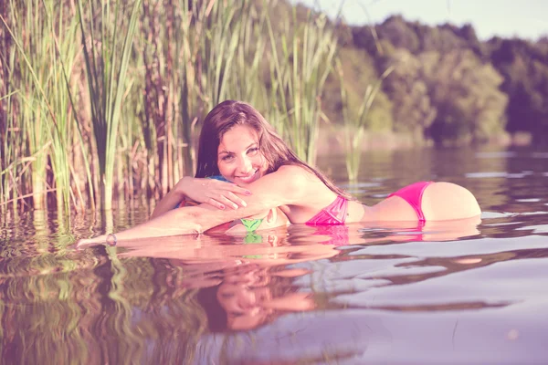 Girl in bikini lying on air ball in water — Stock Photo, Image