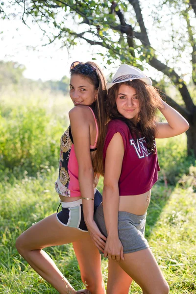 Twee meisjes die zich voordeed op groene tuin — Stockfoto