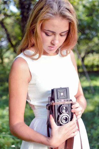 Girl holding and looking at retro camera — Stock Photo, Image