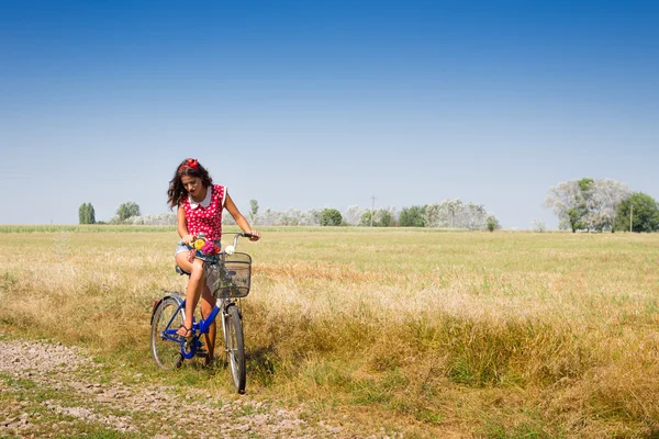 Donna in bicicletta con fiori nel cestino — Foto Stock