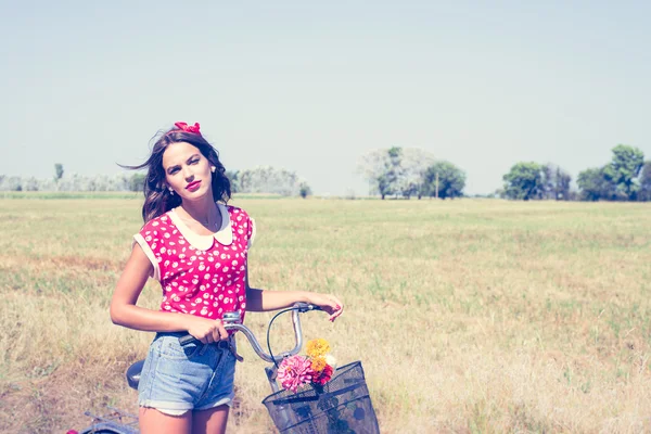 Woman cycling with flowers in basket — Stock Photo, Image