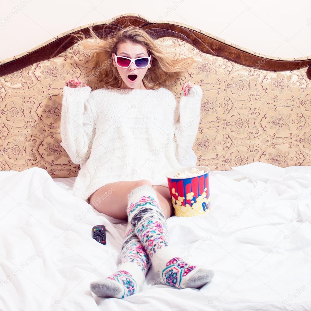 Girl in pajamas sitting in bed in 3D glasses