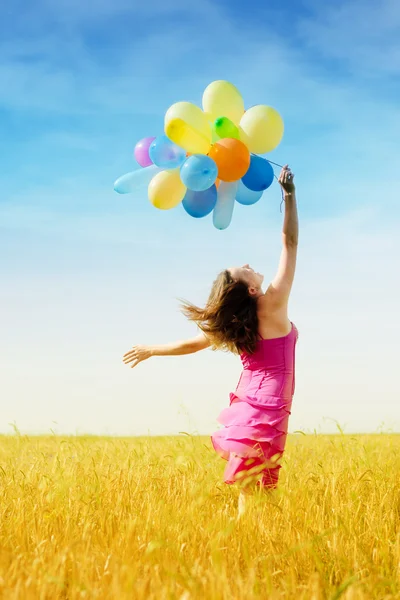Νεαρή γυναίκα με αέρα μπαλόνια στο πεδίο — Φωτογραφία Αρχείου
