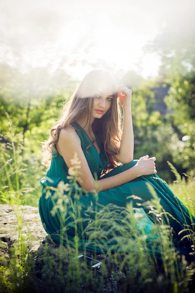 Brunette girl sitting on stone — Stock Photo, Image