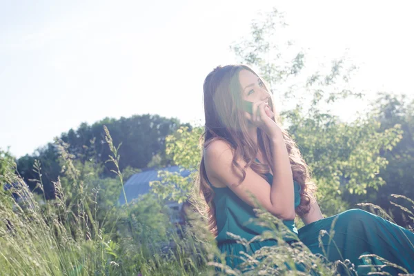 Brunette meisje, zittend op steen in groene jurk — Stockfoto