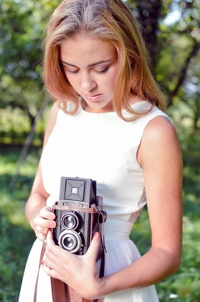 Girl holding and looking at retro camera — Stock Photo, Image