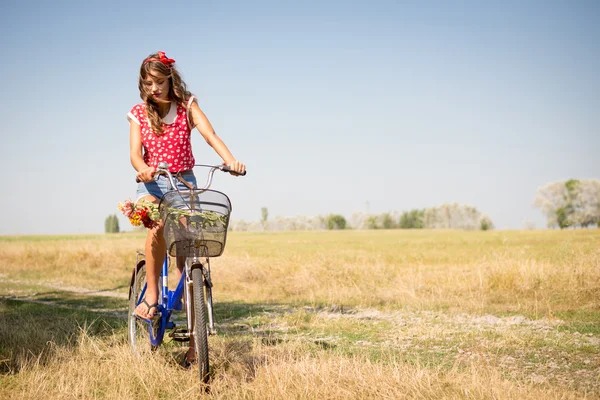 Frau radelt mit Blumen im Korb — Stockfoto