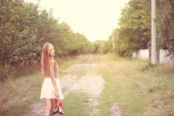 Woman walking barefoot holding shoes in hands — Stock Photo, Image