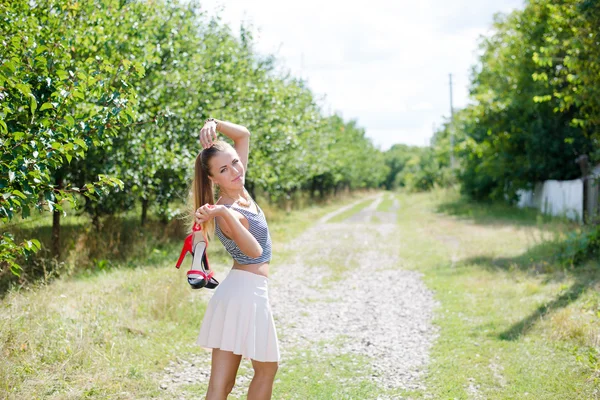 Young woman walking barefoot on country road — Stock Photo, Image