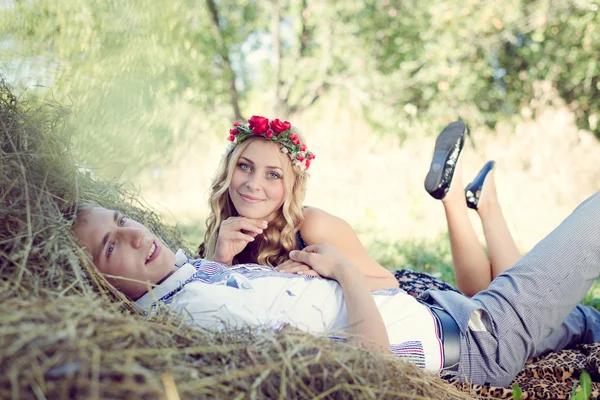 Ungt par kramas på haystack på gröna utomhus — Stockfoto