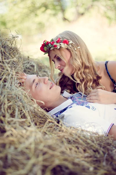 Jovem casal abraçando no palheiro em verde ao ar livre — Fotografia de Stock