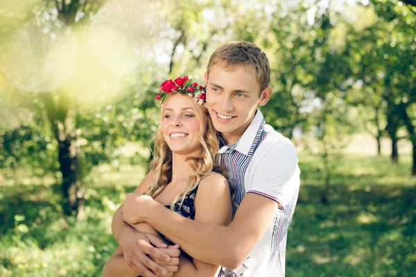 Young couple hugging in autumn orchard — Stock Photo, Image