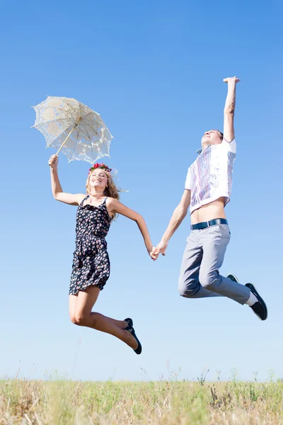 Pareja cogida de la mano y saltando alto en el cielo azul — Foto de Stock