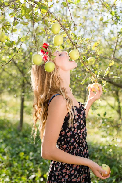 Femme blonde mangeant une pomme jaune d'un arbre — Photo