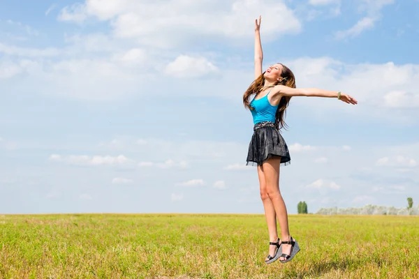 Sexy pretty girl in mini skirt jumping high and happy smiling on blue sky outdoors copy space background portrait — Stock Photo, Image