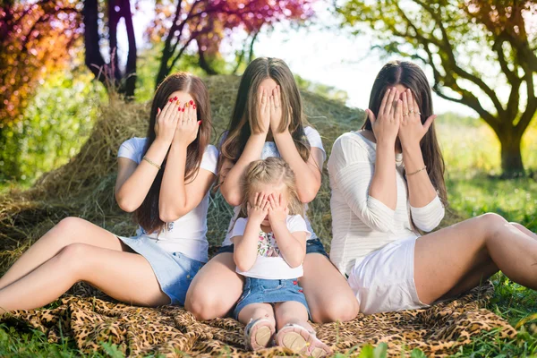 Vier gelukkig meisjes uit klein jong geitje aan tieners verbergen gezichten op zomer hooiberg kopiëren ruimte achtergrond — Stockfoto