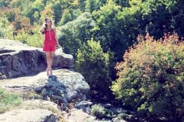 Yaz veya erken sonbahar açık kopya alan arka plan üzerinde hızlı dağ nehir üzerinde uçurumun kenarında duran genç kadın