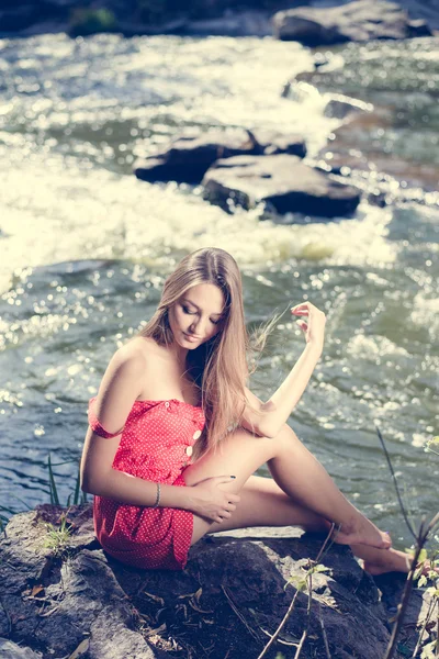 Giovane donna seduta sul bordo della scogliera sopra fiume di montagna veloce in estate o all'inizio dell'autunno spazio esterno copia sfondo — Foto Stock