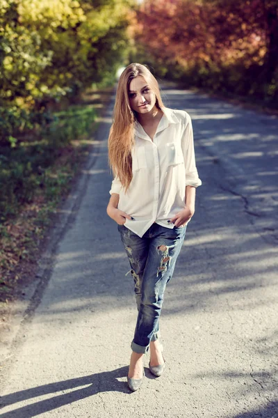 Filtered image of young pretty lady having fun standing on country road on green summer orchard copy space background — Stock Photo, Image