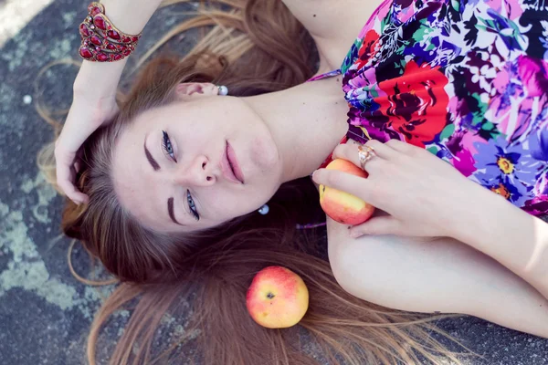 Close up imagem de bela jovem loira sensual menina bonita com olhos azuis deitado com maçãs em pedra pedra ou gelo chão & olhando para longe no retrato espaço cópia — Fotografia de Stock